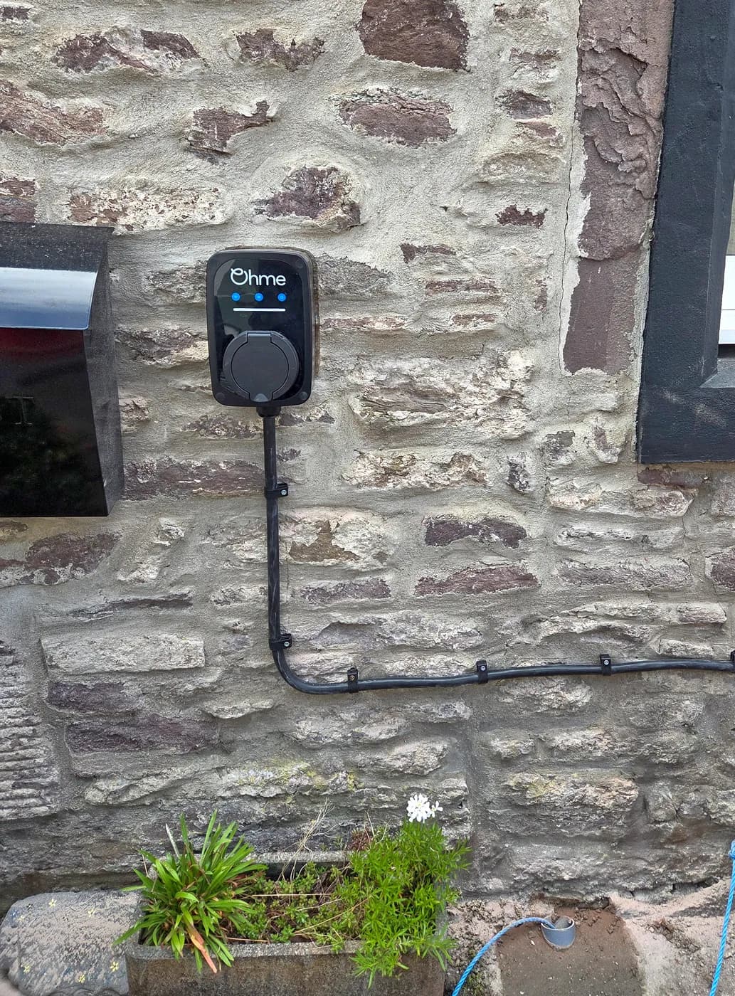 Ohme EV charger fitted to the stone wall of a property in Dunblane