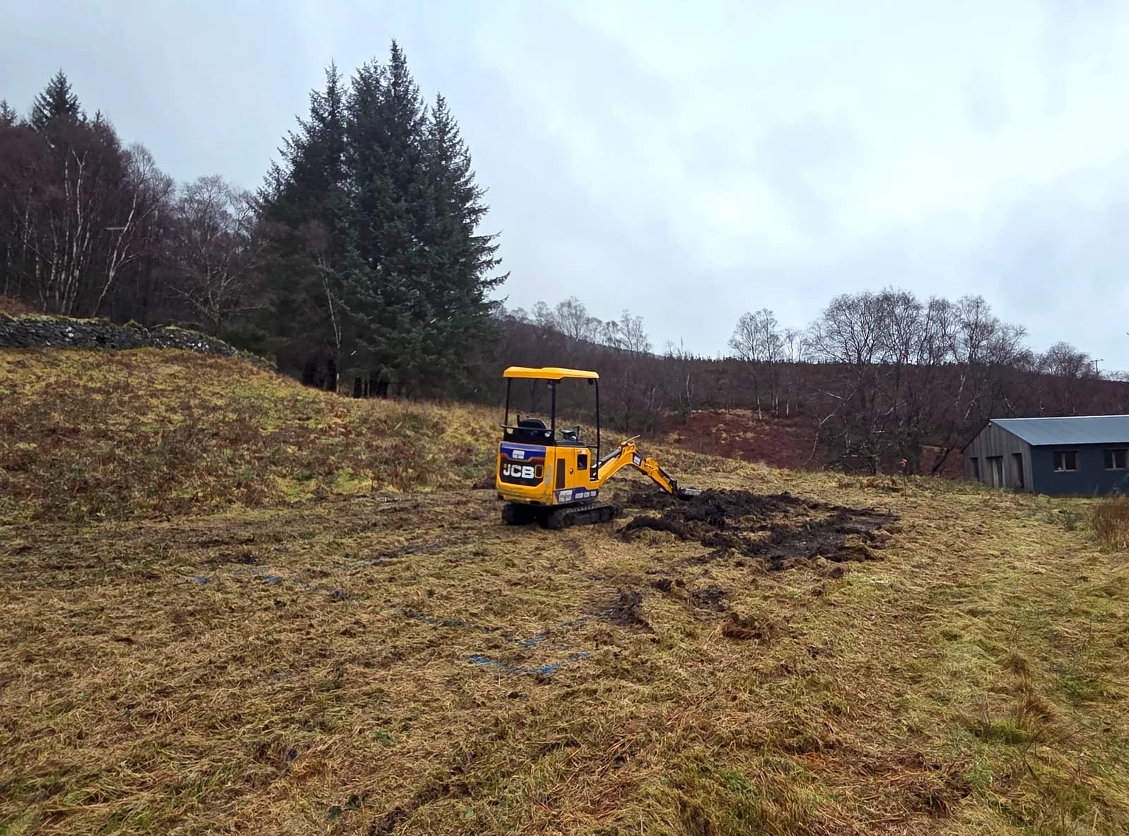 Mini excavator preparing the ground and cable trench for a solar array at Kinlochard